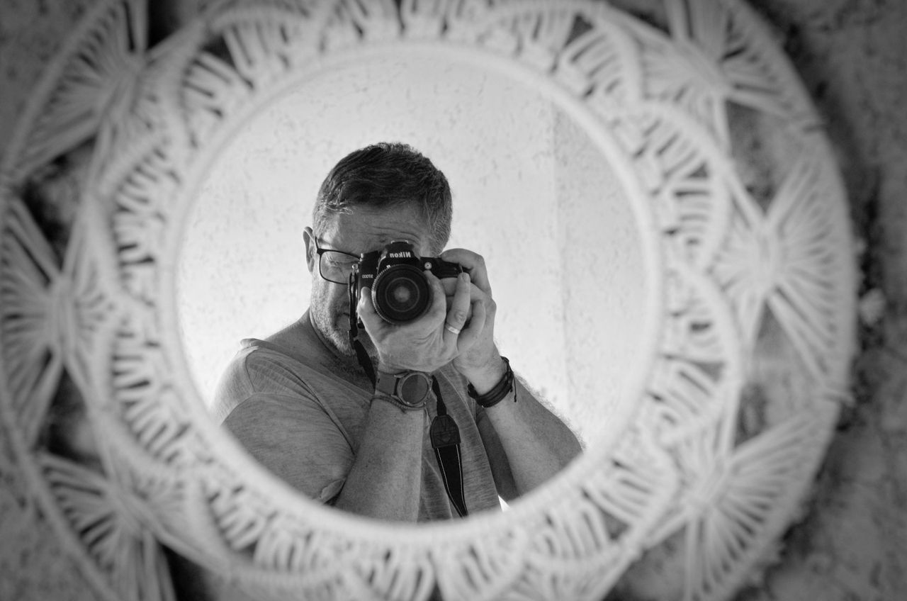 about-03 Black and white self-portrait of a photographer in a decorative mirror reflection.