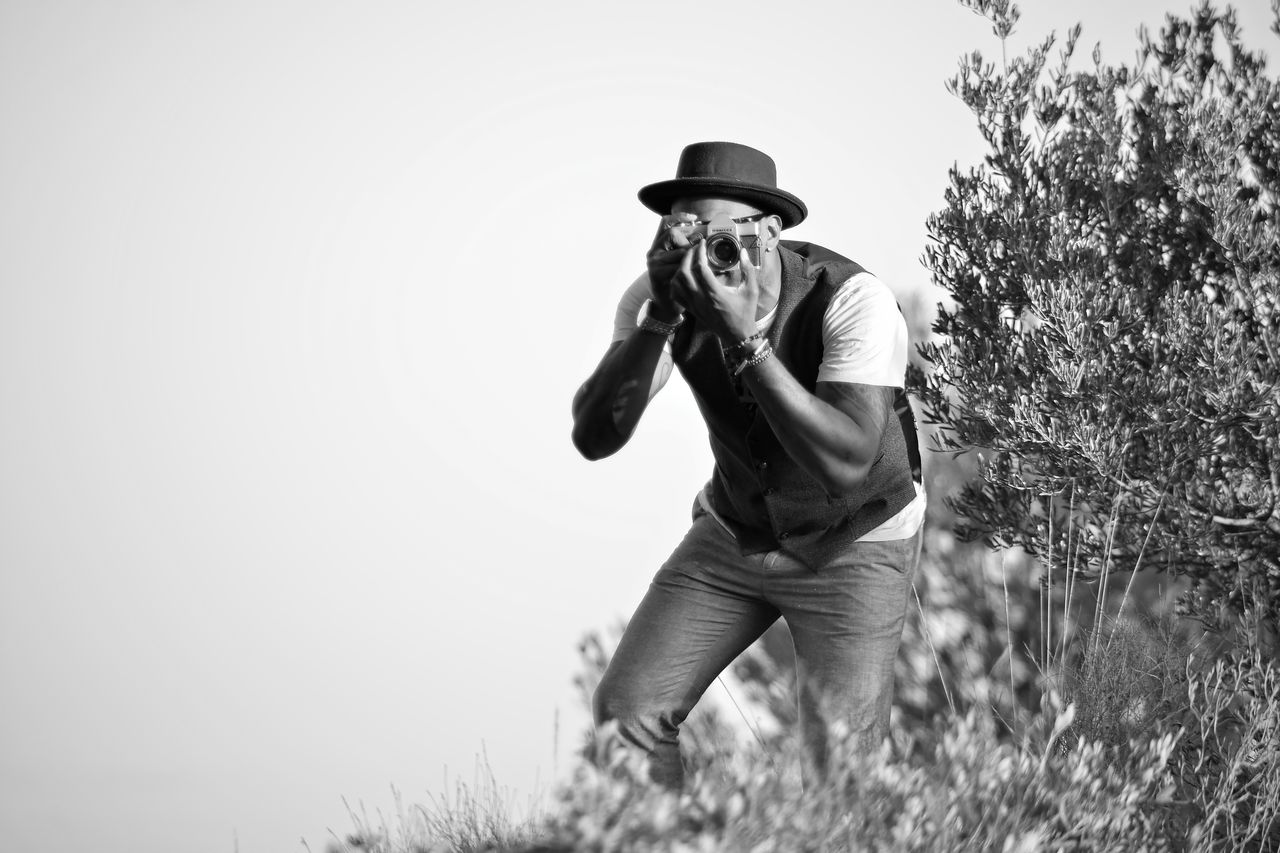 about-04 Black and white photo of a photographer with a vintage camera outdoors.